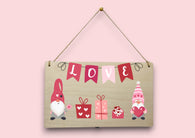 a wooden sign that says love with gnomes and presents