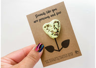 a hand holding a card with a cookie shaped like a flower