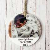 a ceramic ornament with a photo of a baby wrapped in a blanket