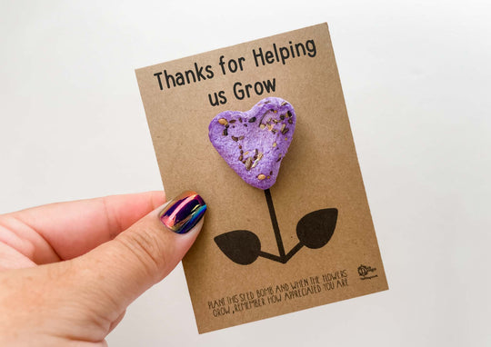 a hand holding a purple heart shaped cookie