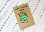 a green brooch sitting on top of a card