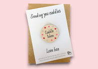 a card with a button saying sending you cuddles