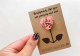 a hand holding a card with a heart shaped cookie on it