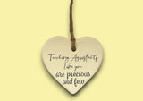 a ceramic heart hanging on a string with a message