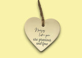 a ceramic heart hanging on a string with a message