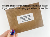 a hand holding a brown envelope with a sticker on it