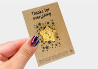 a hand holding a card with a star brooch on it